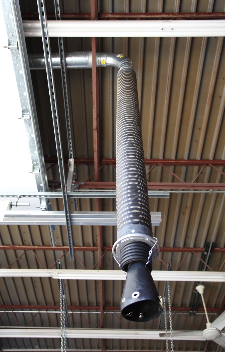 Telescoping exhaust system installed in a service and repair garage, shown hanging down from the ductwork.