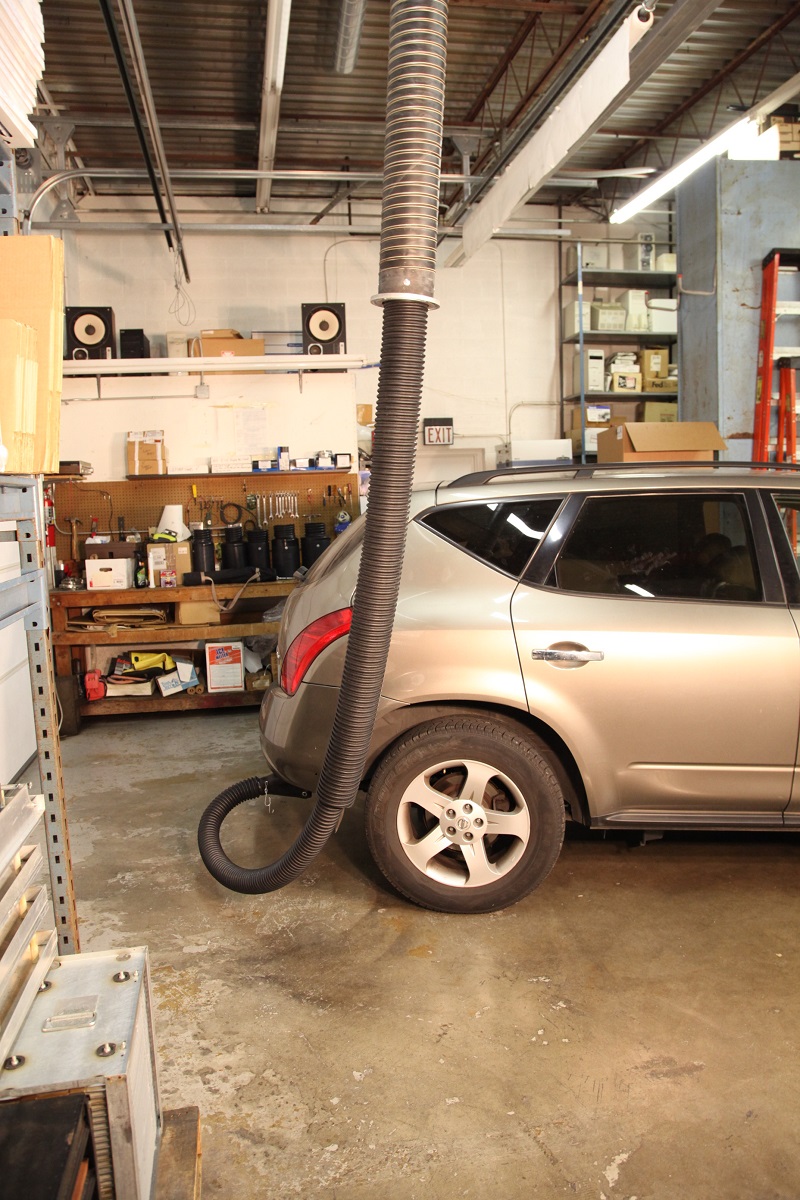 Telescoping exhaust system attached to a passenger vehicle in a service and repair garage.