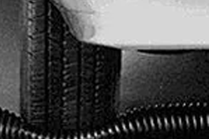 A car tire driving over a crushproof exhaust hose.